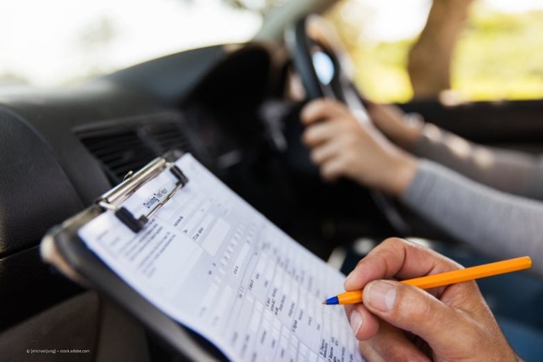 Fahrlehrer macht sich Notizen im Fahrschulauto